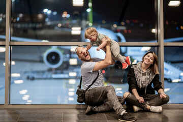 Riga, Latvia - October 19, 2019 - A joyful family moment at the airport: a man playfully holds a...