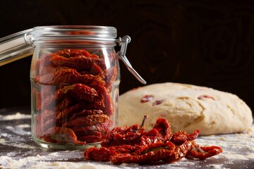 sundried tomatoes in jar beside pizza dough