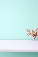 Pink cherry blossoms in vase on turquoise wall background.