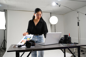 Beautiful young photographer using laptop in modern photo studio