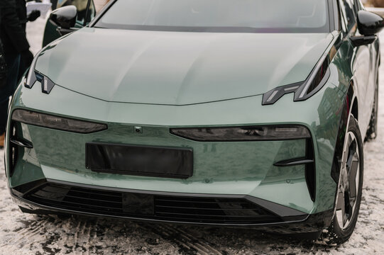 Bumper closeup and wheel. The front light on a new modern green electric sedan car. Modern concept supercar exterior design detail - headlight. Right and left turn indicator signal. Concept of future.