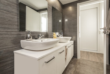 Bathroom of a house with wooden sink cabinet with beveled mirror