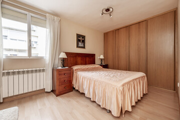 bedroom with double bed with salmon-colored satin duvet and built-in wardrobe covering a wall