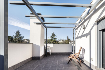 Terrace on the attic floor of a single-family home with gray stoneware floor and folding teak wood...