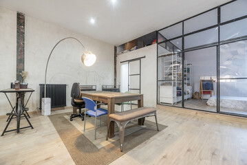 Open loft-style home with transparent partitions, industrial-style wood and metal furniture, and unpainted walls
