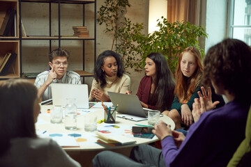 Group of young people, student siting in library, studying together, doing projects together and preparing for exam. Concept of education, youth, knowledge, homework, exams, projects.