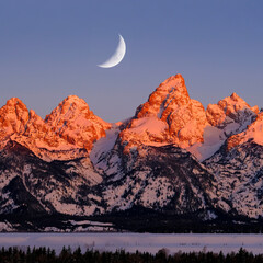 Sunrise on Teton Mountain Range in Wyoming Alpen Glow Orange and Pink on Rugged Mountains with Crescent Moon