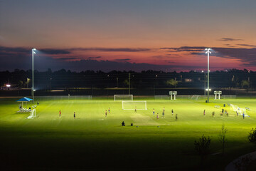 Sportsmen training in soccer game on illuminated football stadium in public sports park in North Port, Florida