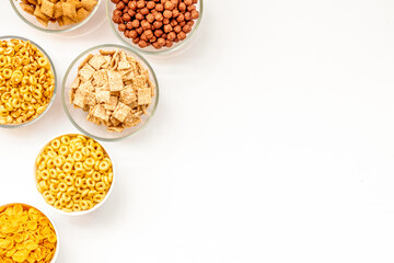 Various corn cereals in bowls on white background top view copyspace