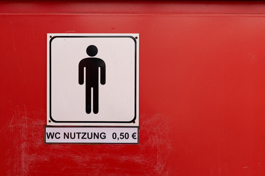 Schild mit der deutschen Aufschrift WC Nutzung 0,50 € an einer Toilette für Männer