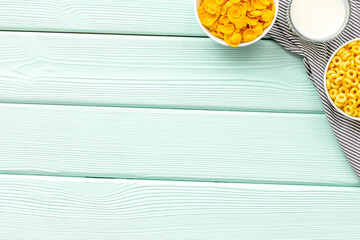 cereals, oatflakes and cornflakes with milk for healthy breakfast on mint wooden background top...