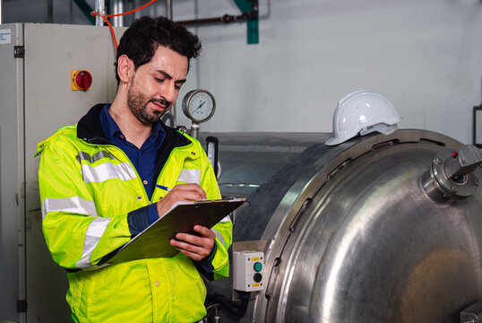 Portrait of confident factory engineer maintaining a record on clipboard in food factory production line.