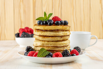 Delicious pancakes with fresh berries on white wooden table. Food concept.