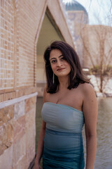 Fototapeta premium A woman in a blue and white dress stands in front of a brick wall