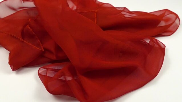 Translucent bright red chiffon shawl slowly falls to the white floor, slow motion