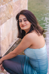 A woman is sitting on a stone wall with her back to the camera