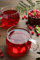 Tasty hot cranberry tea in glass and fresh berries on wooden table