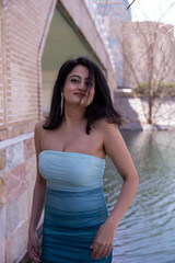 Fototapeta premium A woman in a blue and white dress stands in front of a bridge