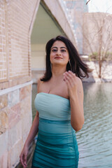 Fototapeta premium A woman in a green and blue dress is standing in front of a bridge