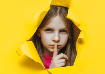The little girl closes her lips with her index finger, making it clear to the viewer that they need...
