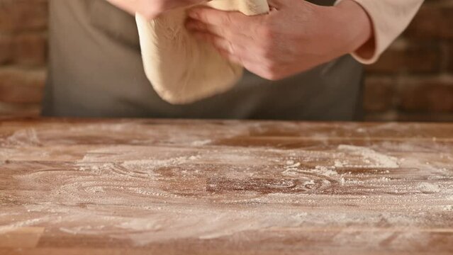 women's hands knead and stretch the dough. hands make a dough wrap and form it into a proofing ball.