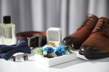 Wedding stuff. Composition with stylish boutonniere on white surface, closeup