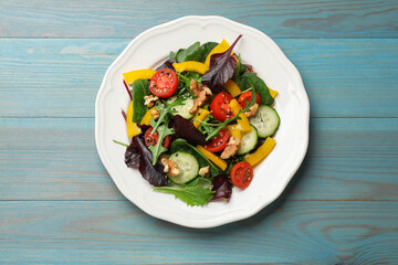 Tasty fresh vegetarian salad on light blue wooden table, top view