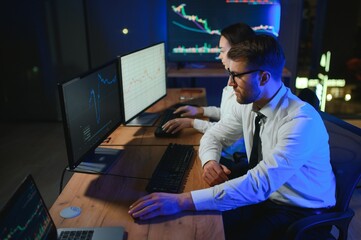 Team of traders working at monitor computer and browsing online in trading office