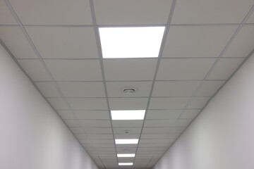 White ceiling with PVC tiles and lighting indoors, low angle view