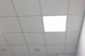 White ceiling with PVC tiles and lighting indoors, low angle view