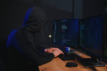 hacker sitting at desk in dark atmosphere. A computer programmer or hacker. Anonymous computer...