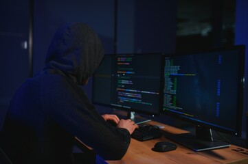 hacker sitting at desk in dark atmosphere. A computer programmer or hacker. Anonymous computer...