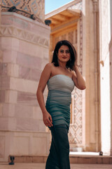 A woman in a blue and white dress stands in front of a building