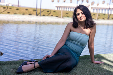 A woman is sitting on the grass by a body of water