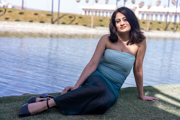 A woman is sitting on the grass by a body of water