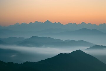 Misty mountain layers at sunrise with a gradient sky.