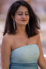 A woman with long hair and a blue dress is sitting and looking at the camera