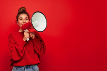 Announcing Discounts Sale. Young woman with Megaphone in Lifestyle Travel Concept. Red Studio Isolated Background with Copy Space