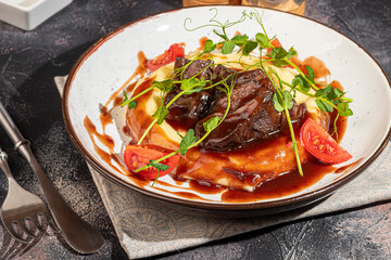 Mashed potatoes with beef in sweet and sour sauce, decorated with tomatoes and microgreens.