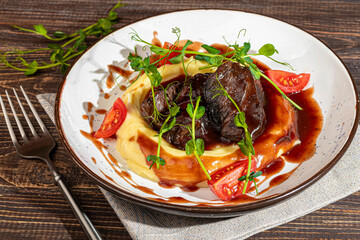 Mashed potatoes with beef in sweet and sour sauce, decorated with tomatoes and microgreens.