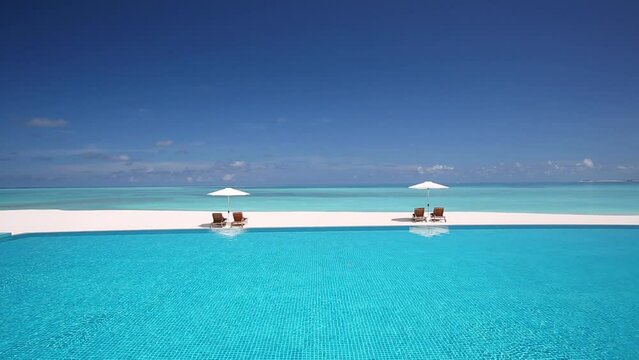 Deck chairs and infinity pool over amazing tropical lagoon, The Maldives, Indian Ocean, Asia