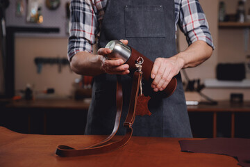 Tailor man hold product from natural leather brown color on workshop background. Concept bag and shoemaker industry business