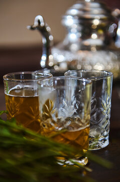 Drinking glasses with traditional North African tea and silver teapot on blurred background. Moroccan mint tea. Close-up