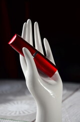lipstick on a white porcelain stand in the shape of a hand close up