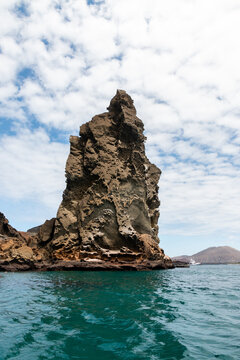 pinaculo de roca volc&aacute;nica con volc&aacute;n de fondo en bah&iacute;a de agua turquesa en Gal&aacute;pagos