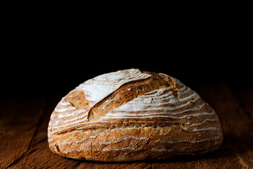 Wheat artisan sourdough bread on a wooden table black background. 