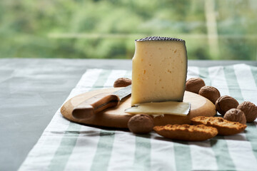 Artisan Cheese on Wooden Board With Crackers and Nuts by Window Light