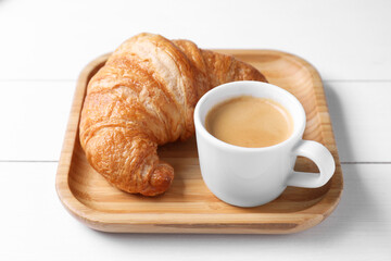 Fresh croissant and coffee on white wooden table. Tasty breakfast