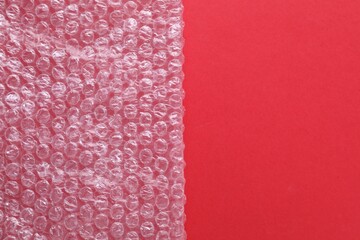 Transparent bubble wrap on red background, top view. Space for text