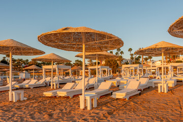View of tropical beach with umbrelles during sunset. Holiday vacation and travel concept.